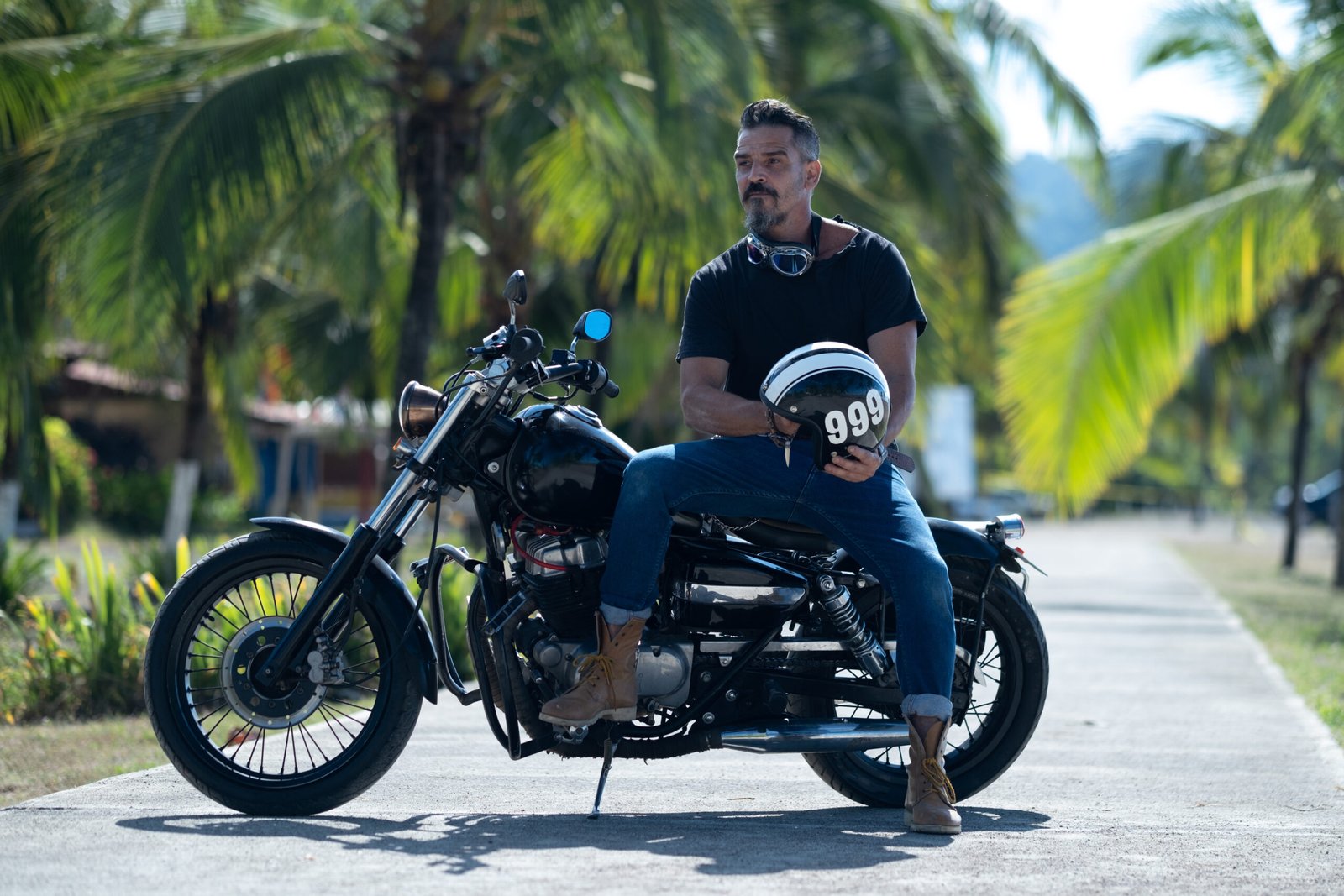 Male biker with a thick beard poses on a motorbike